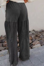 Dark gray mineral wash wide leg trousers with layered ruffle waist detail and distressed patchwork accents