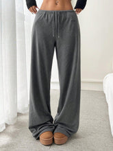 Gray relaxed fit drawstring pants with wide-leg design and black brand tag on the side for comfortable wear