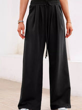 Black wide-leg sweatpants with tied elastic high waist and drawstring featuring pleated solid design