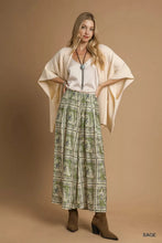 A flowing sage green and cream umgee bohemian print pants with intricate white embroidered designs and pockets