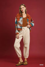A woman wears beige Umgee fleece jogger pants with drawstring waist paired with a rust-colored suede jacket