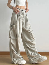 Drawstring wide leg cargo pants in light beige slightly shiny fabric with large side pockets and black button closures