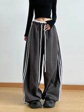 Black wide leg drawstring pants with white side stripes and adjustable waistband for comfortable casual wear