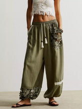 Olive green drawstring harem pants with loose fit and lace floral embroidery on pockets and cuffs