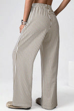 Beige and black vertically striped wide-leg trousers with elastic high waist and pockets for a loose fit