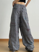 Gray plaid wide leg pants with drawstring waist featuring bold graphic print with red stars and black text