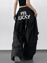 Back view of black letter back wide leg drawstring pants with yes lucky printed in bold white letters