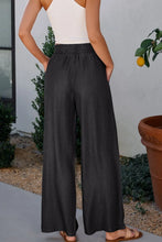 Black wide-leg smocked high waist pants with elastic waistband subtle texture and side pockets