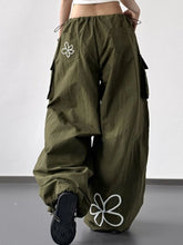 Olive green drawstring wide leg cargo pants with white embroidered flower designs on pockets and lower leg