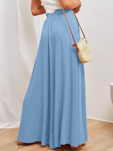 A flowing light blue wide leg pants with gathered waistband made of soft lightweight fabric with pockets