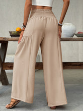 Beige smocked waist wide leg pants with high-waisted elasticated waistband and subtle side pockets