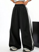 Black wide leg striped track pants featuring two parallel white stripes on each outer leg for casual wear
