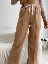 Tan high-waisted casual pants with a wide leg drawstring waistband and straight-leg cut for comfortable wear