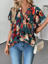 A vibrant teal abstract print ruffle sleeve blouse with bold red orange cream floral pattern and button-down front