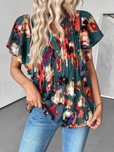 A vibrant abstract print ruffle sleeve blouse with bold red orange and teal floral pattern on dark green fabric