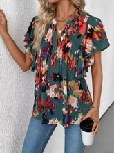 A vibrant short-sleeved abstract print ruffle sleeve blouse with teal red orange and purple floral pattern and pleated front