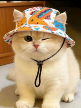 Fluffy cream cat in adjustable chin strap pet bucket hat with fish pattern