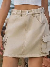 Beige denim skirt with adjustable waist and cargo pockets featuring a belt looped at the waist