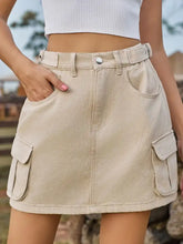 Beige adjustable waist denim skirt with cargo pockets and belted waist in a mini length design