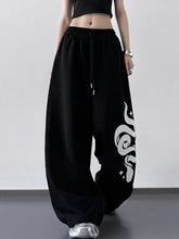 Black wide leg drawstring pants with a bold white snake graphic on the side in wide leg sweatpant style