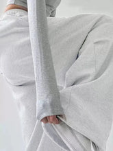 A soft heather gray long-sleeved sweatshirt with ribbed cuffs paired with oversized wide leg drawstring pants