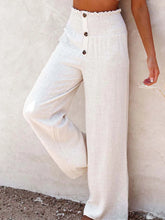 White high-waisted textured wide leg pants with smocked waistband and three dark buttons down the front