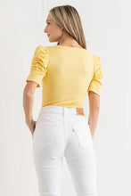 Yellow shirring puff sleeve bodysuit with fitted silhouette paired with white jeans featuring classic Levi’s patch back view