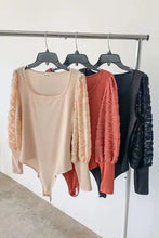 Beige textured puff sleeve bodysuit with lace trim long sleeves square neckline and side tie detail