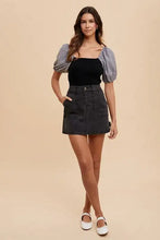 Black denim mini skirt by Annie Wear featuring button front and side pockets in a cargo denim mini style