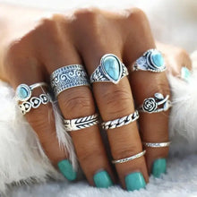 Hand with multiple artificial turquoise alloy rings in 10-piece set