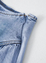 Light-wash denim mini skirt with asymmetric ruffle overlay and visible stitching details in a subtle faded blue hue