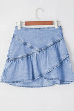 A light blue denim mini skirt with asymmetric tiered ruffle overlay and visible stitching details