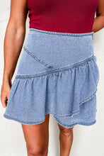 Light-wash denim mini skirt with asymmetric ruffle overlay and elastic waistband in a tiered design