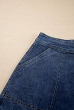 Asymmetrical denim skort in blue with high waist, pockets, and button closure