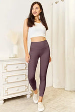 Woman in mauve wide waistband sports leggings and white crop top