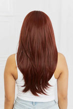 Woman with long layered reddish-brown hair in Auburn Wave Synthetic Wig with Bangs, Cap Included