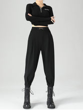 Black high-waisted tapered pants in polyester fabric with pleats and a metallic chain buckle for a perfect fit