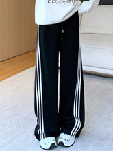 Black striped wide leg pants featuring three white vertical stripes down each leg for casual wear
