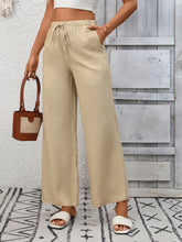 Beige drawstring high waist wide leg pants featuring a high waist wide fit with side pockets and a comfortable drawstring waist