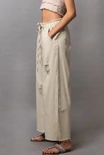 Beige denim pol distressed drawstring slit wide leg pants with distressed patches and a drawstring waist