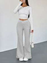 A pair of light gray high waisted flare leg pants with soft textured fabric and subtle vertical seam detailing