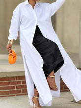 White oversized button-down shirt with long flowing silhouette and side slits paired with wide leg pleated pants