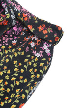 Black floral high rise wide leg pants featuring vibrant orange pink and yellow blossoms on dark fabric