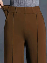 Brown high-waisted wide leg pants with pleated front and elastic waistband suitable for machine wash and tumble dry