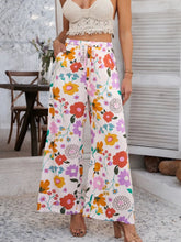 White floral print devine drawstring pants featuring vibrant orange pink purple blossoms on flowing wide-leg fabric with care instructions