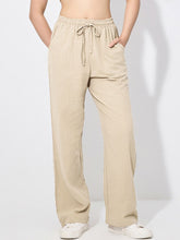 Beige drawstring wide leg pants with relaxed fit jogger style elastic waistband and matching drawstring closure