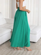 A flowing emerald green wide leg pants with high waist soft pleats and functional pockets for versatile wear