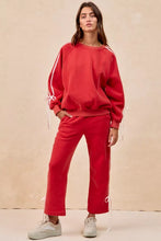 Red oversized fleece sweatshirt with white striped sleeves and lined bow details drawstring ties at the cuffs