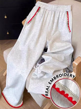 Light gray casual loose fit sweatpants with red scalloped embroidered trim along side seams and cuffs