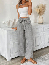Full size plus size paper bag waist pants with black and white vertical stripes and self-tie belt at the waist